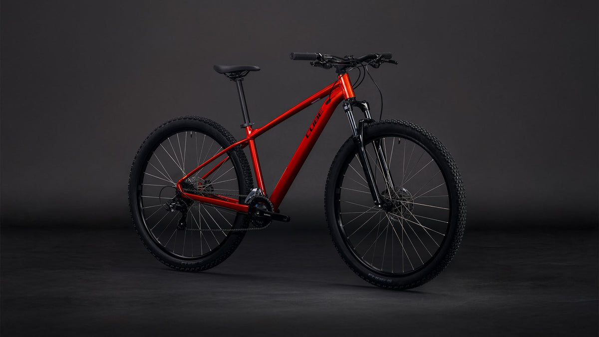 Bicicleta de montaña CUBE Aim ONE 2026 color sundowner & black vista lateral completa sobre fondo negro